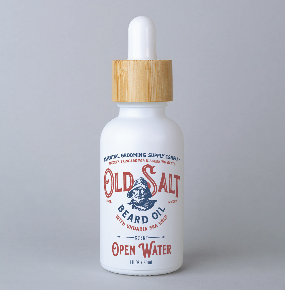 White bottle with wood dropper cap Label reads " Essential Grooming Spply Company, Modern Skincare for discerning gents. Old Salt Beard Oil with undaria sea kelp, Scent Open Water" an image of a sailor in the center.