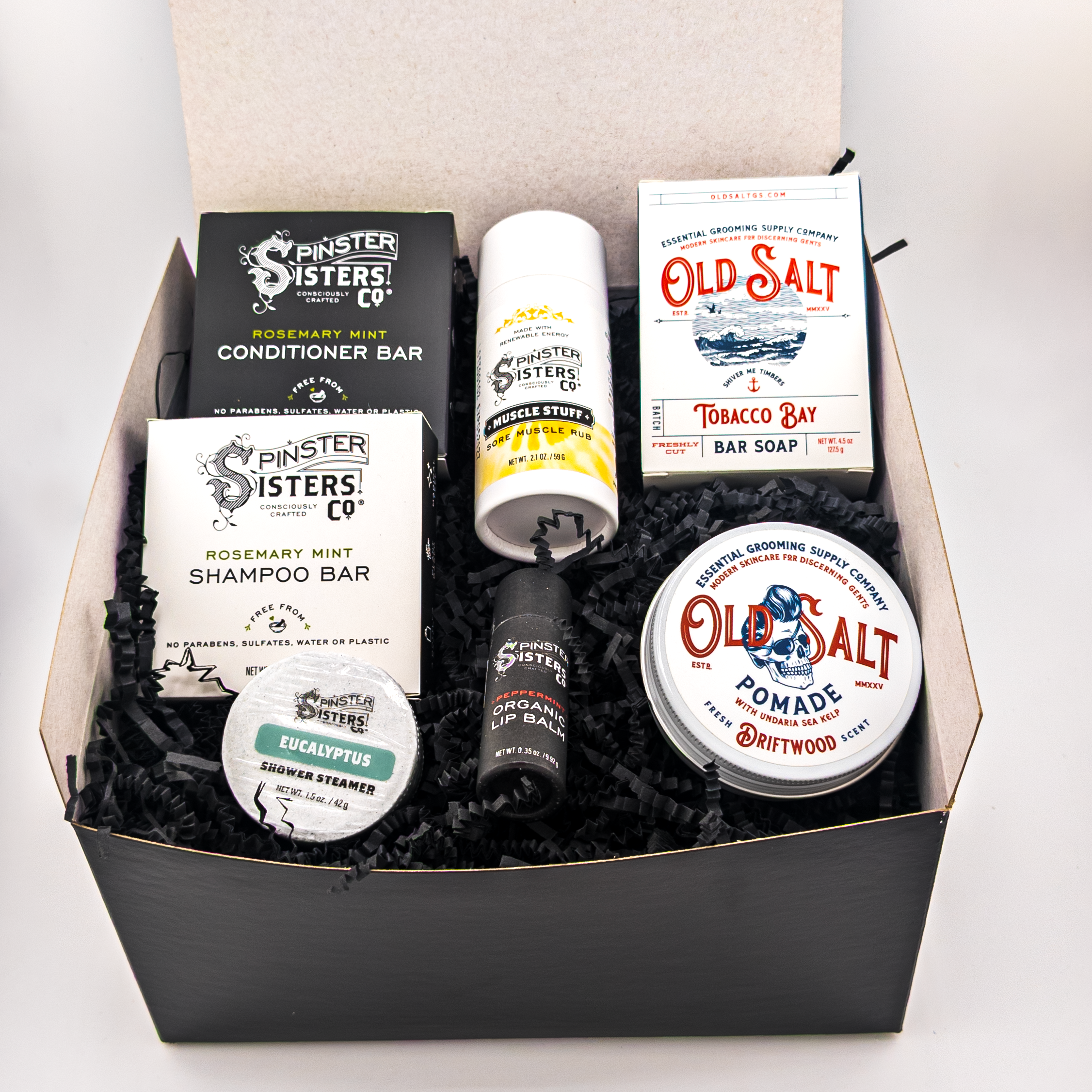 Black Gift box filled with Rosemary Mint Shampoo and Conditioner, A Eucalyptus Shower Steamer, Muscle Stuff, A Peppermint Lip Balm,  Boxed Old Salt Tobacco Bay bar soap, and a tin of Old Salt Driftwood Pomade