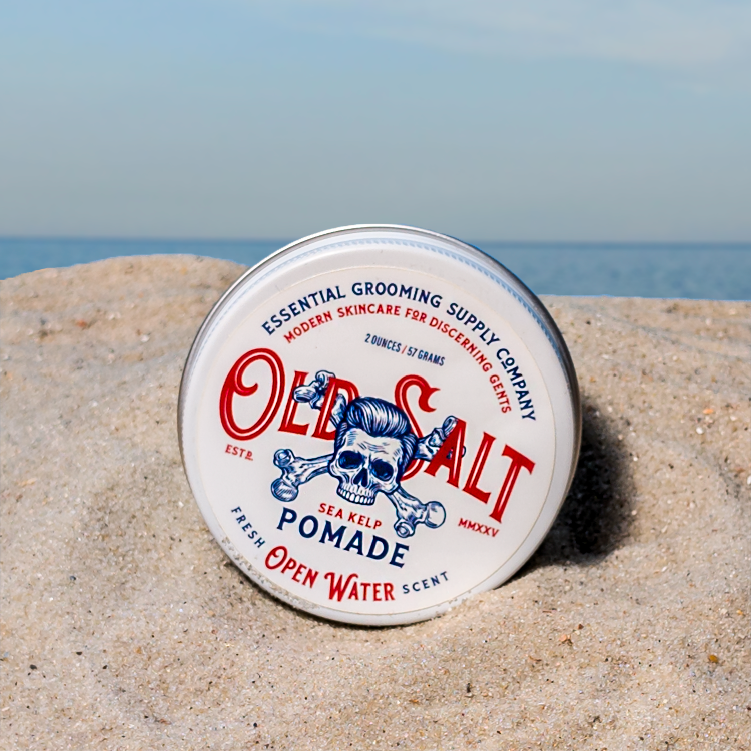 Tin of Old Salt Pomade in Open Water Scent on a Sandy beach
