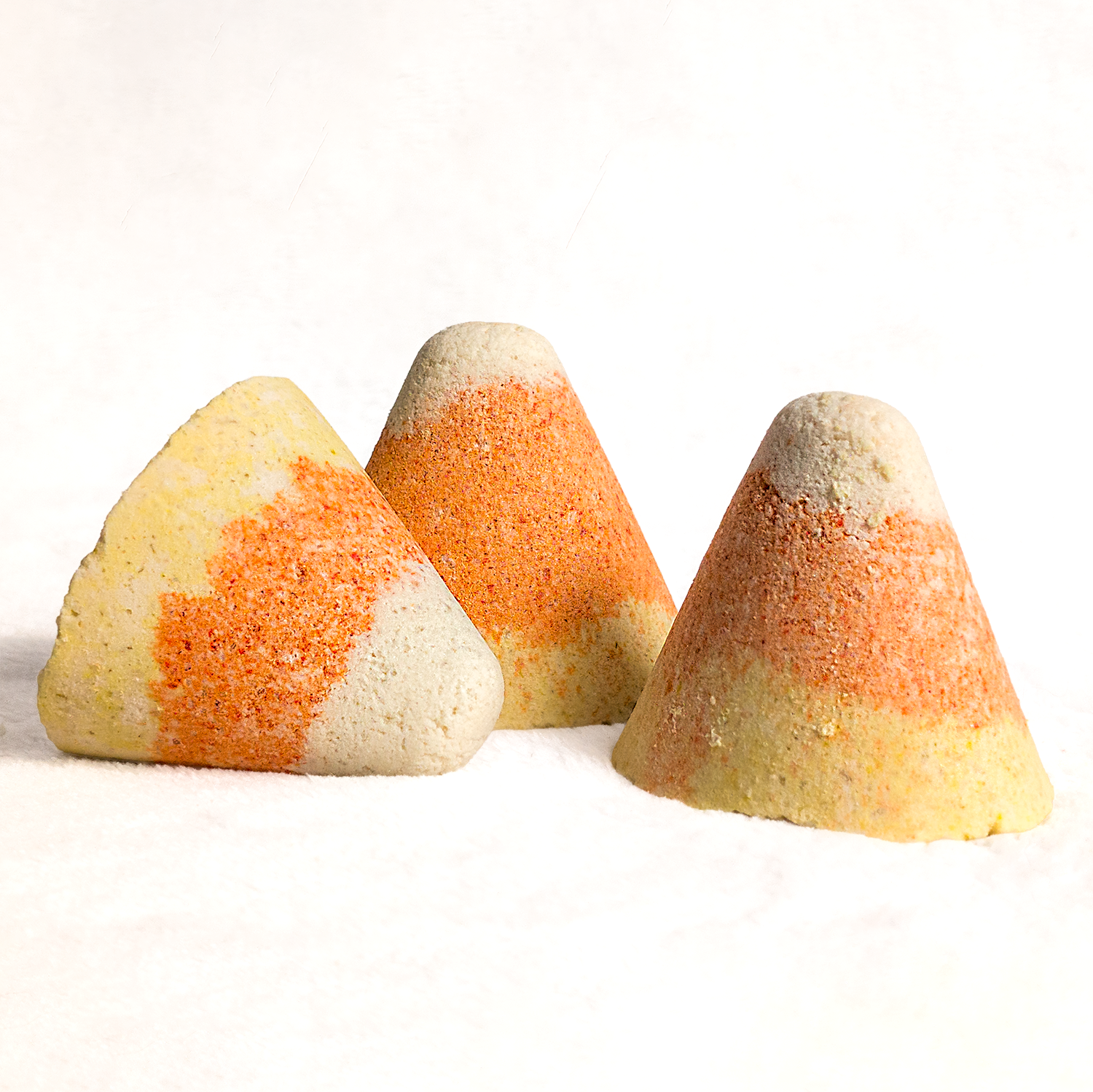 Three candy corn-shaped Bath Bombs on a white background
