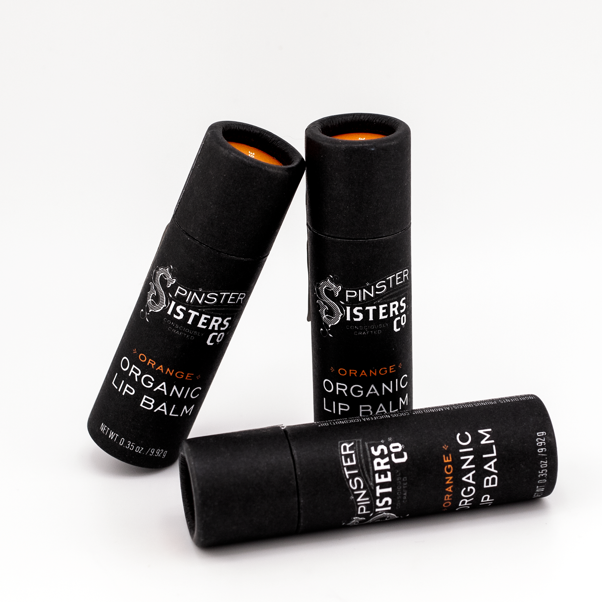 3 black paper tubes that say "Spinster Sisters Orange Organic Lip Balm" 