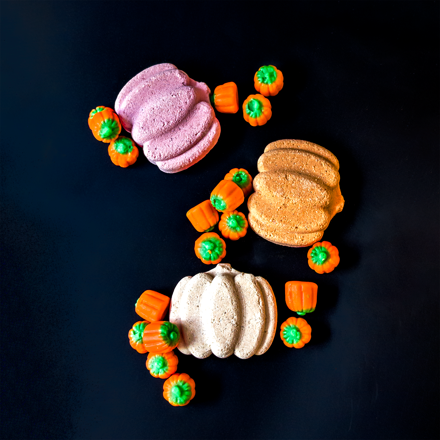 Assorted Pumpkin Bath Bombs on Black Background  surrounded by Orange and Green Pumpkin Candies